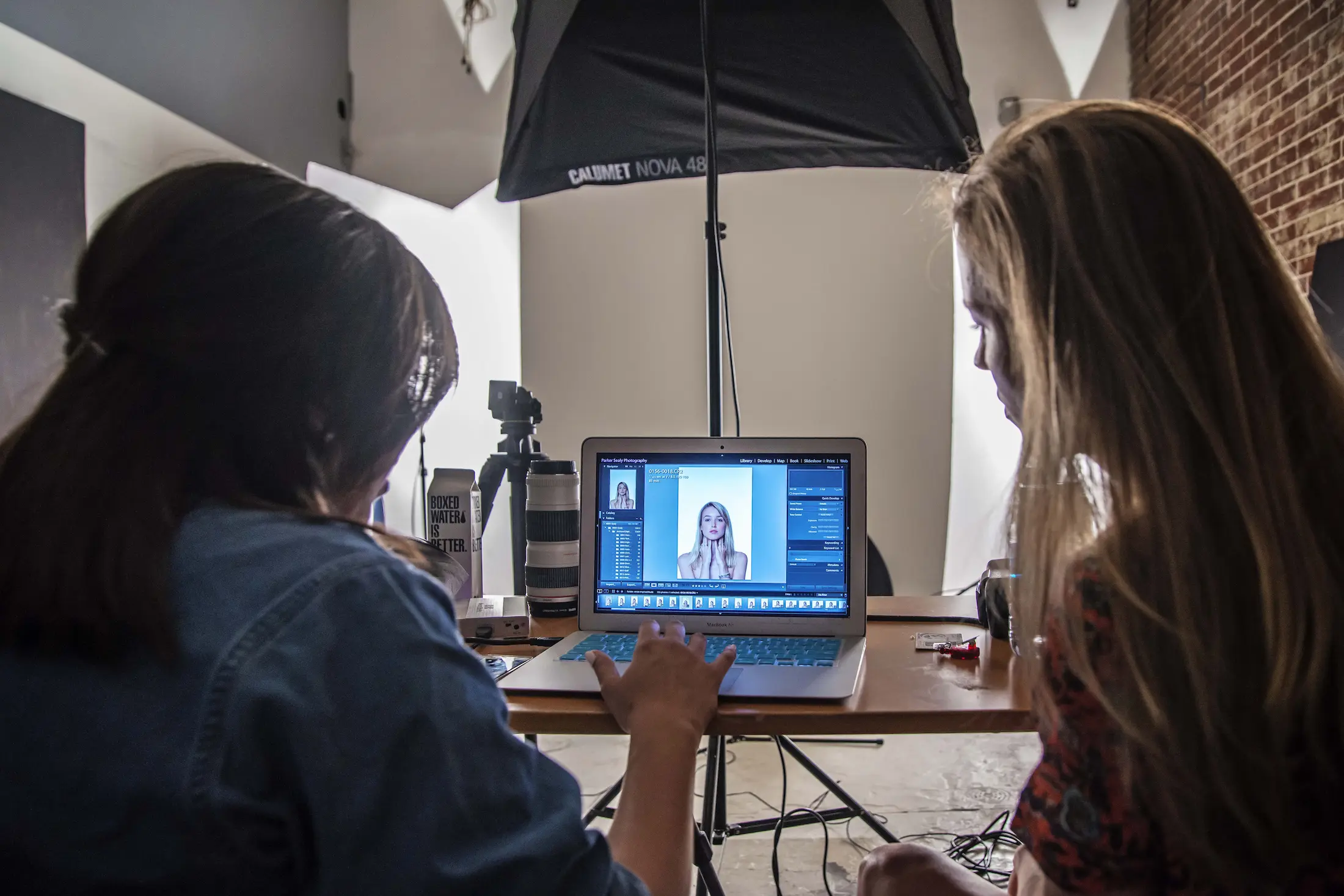 Two students collaborating at a laptop while working on a photo shoot